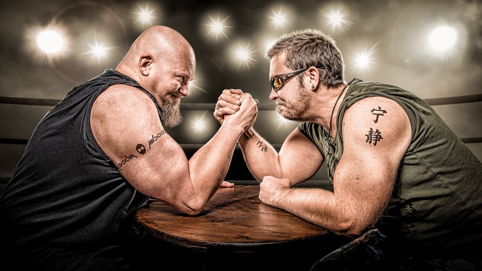 Two men arm wrestling with tattoos