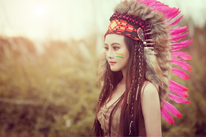 Woman wearing a Native American headdress with face paint