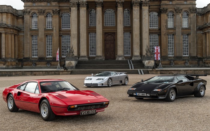 Three classic sports cars in front of a palace