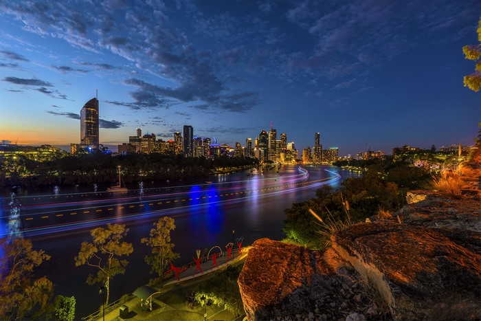 Brisbane skyline at night with river and rocks