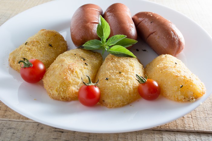 Fried potato croquettes with sausages and tomatoes
