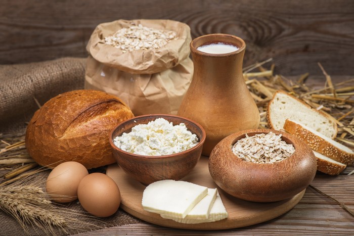 Dairy products, bread, eggs, and oats on a wooden table