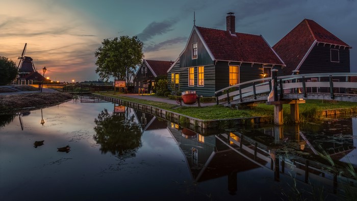 Dutch village with canal and windmill at dusk