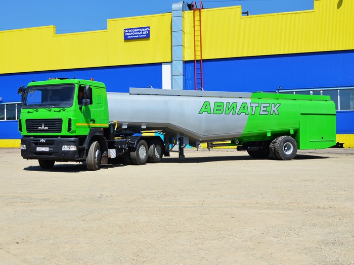 Green MAZ truck with a silver and green trailer