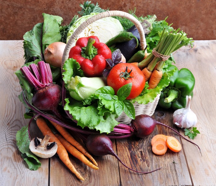 Basket of fresh vegetables on wooden planks
