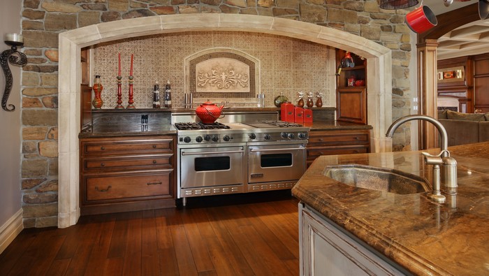 Kitchen with stone archway, range, and sink