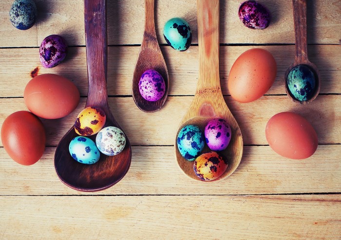 Easter eggs in wooden spoons on wood planks