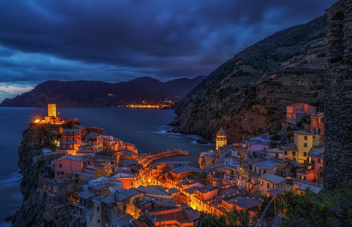 Vernazza, Italy at night with illuminated houses on a cliff by the sea