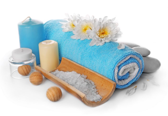 Spa items: blue towel, candles, salt, stones, and flowers