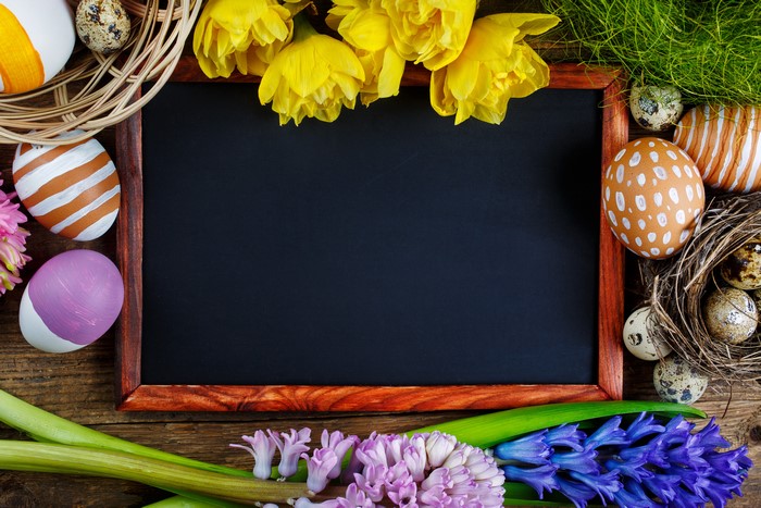 Easter eggs and flowers on a wooden background with a chalkboard
