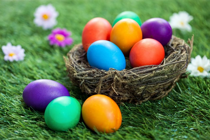 Easter eggs in a nest on grass with flowers