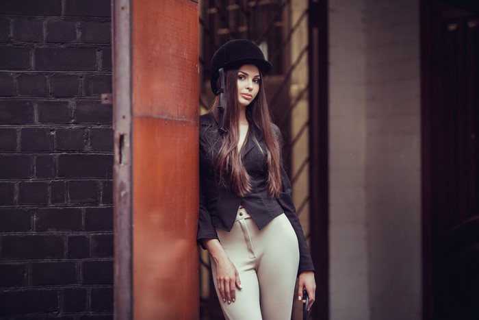 Woman in equestrian uniform leaning against a door