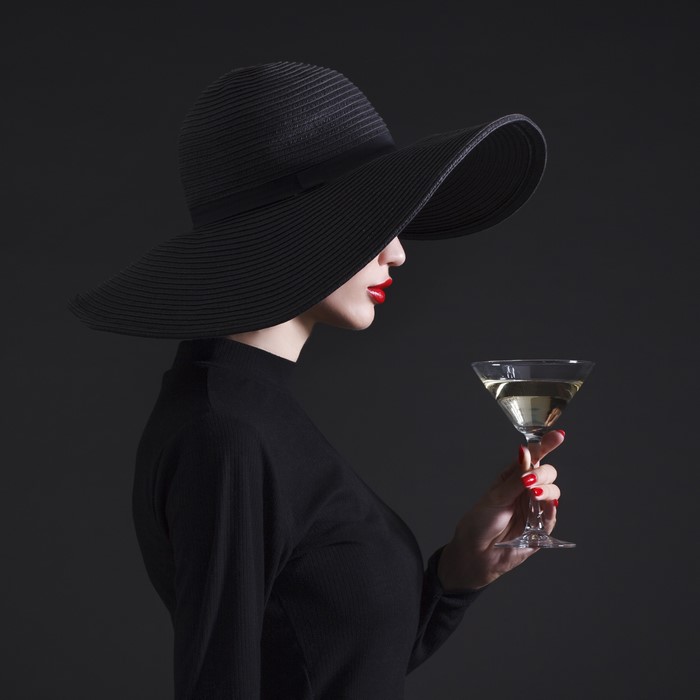 Woman in black hat holding a cocktail