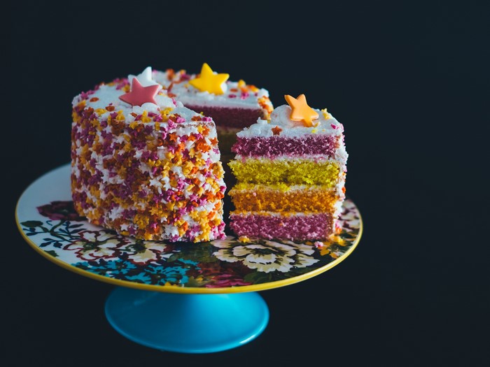 Colorful layered cake with star sprinkles on a cake stand