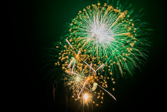 Green and yellow fireworks exploding in the night sky