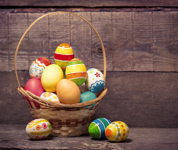 Easter eggs in a wicker basket on wood planks