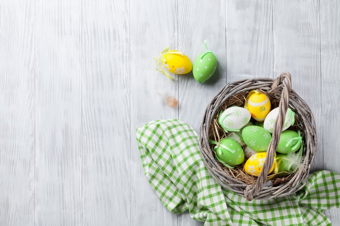 Easter eggs in a wicker basket on wood planks
