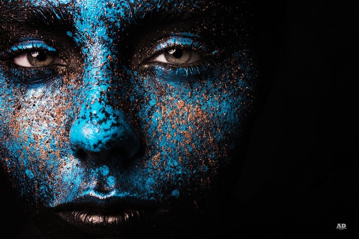 Close-up of a face with blue and gold makeup