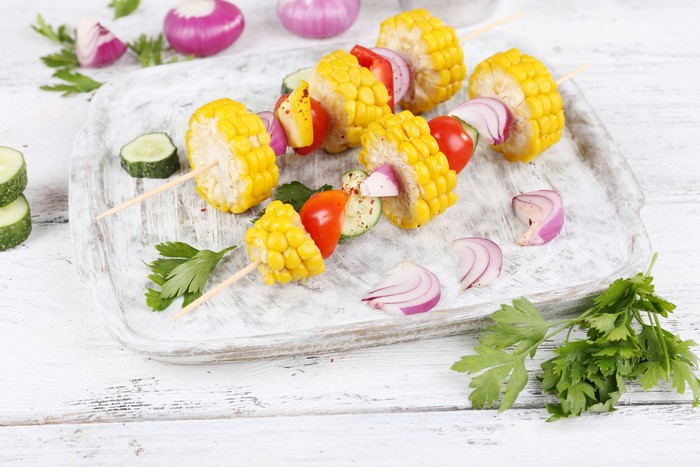 Corn and vegetable skewers on a cutting board