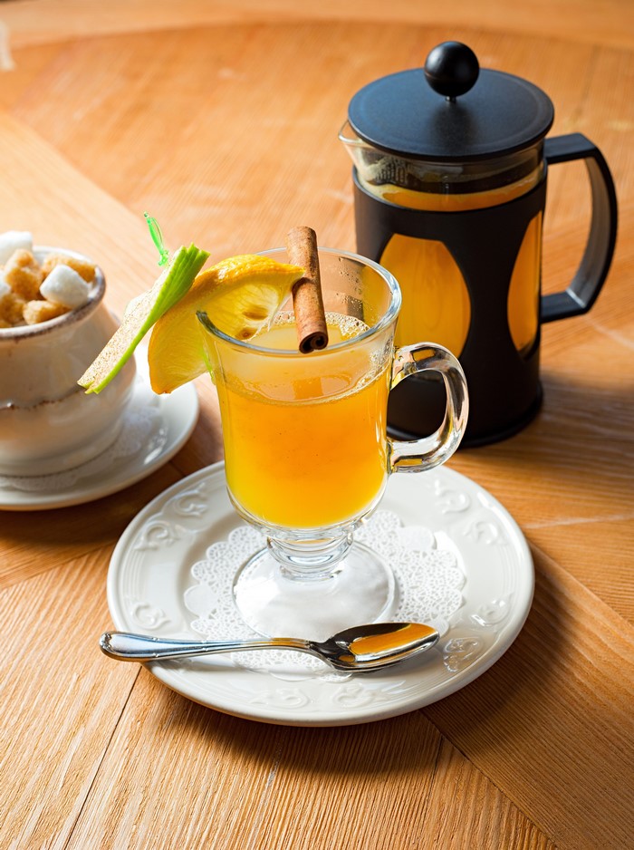 Hot drink with lemon and cinnamon stick in a glass mug