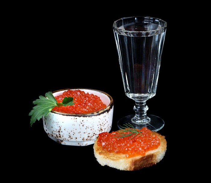 Red caviar in a bowl and on toast with a shot glass of vodka