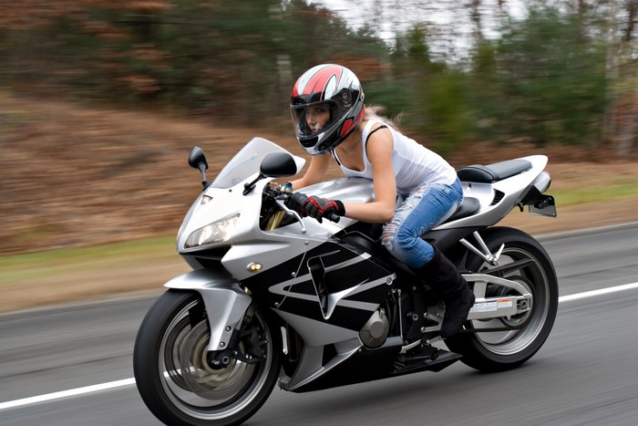 Woman riding a silver motorcycle on a road