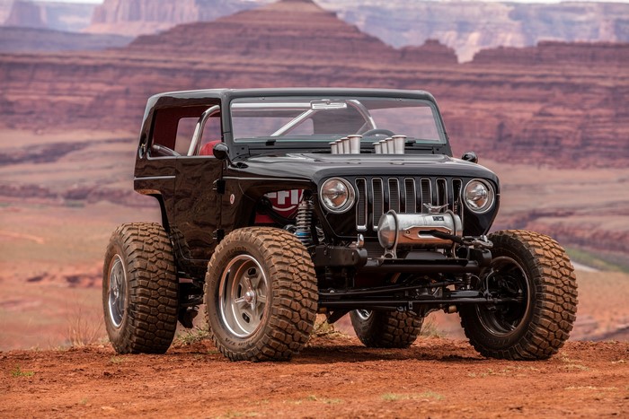 Black Jeep Wrangler with large tires in desert landscape
