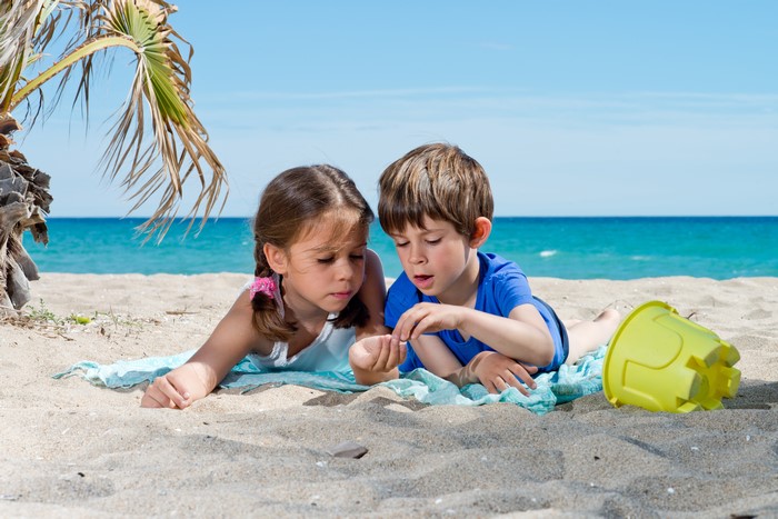 Two children looking at a shell on the beach
