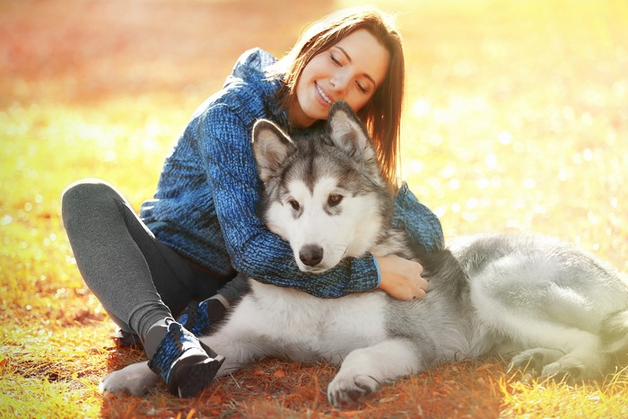 Woman hugging a husky dog outdoors