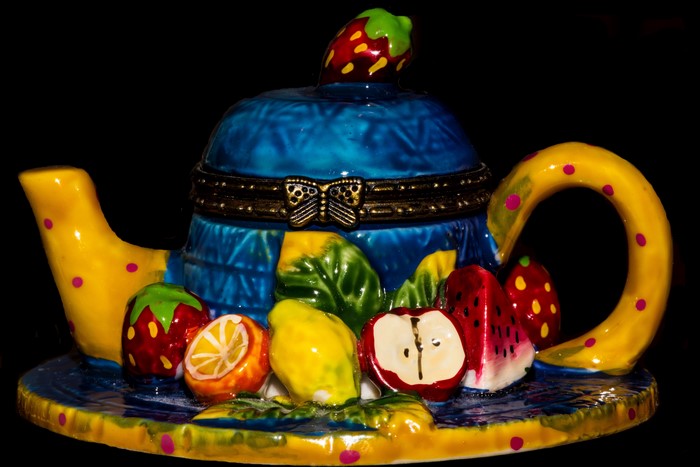 Decorative teapot with fruit design on black background