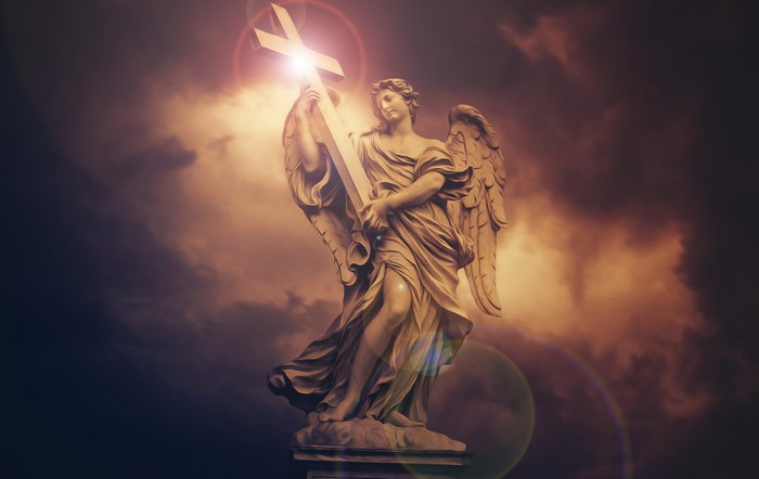 Angel sculpture holding a cross against a cloudy sky