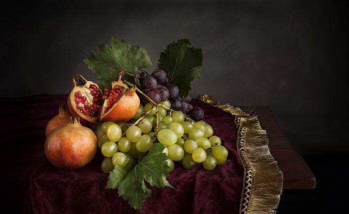 Still-life with grapes and pomegranates on a table