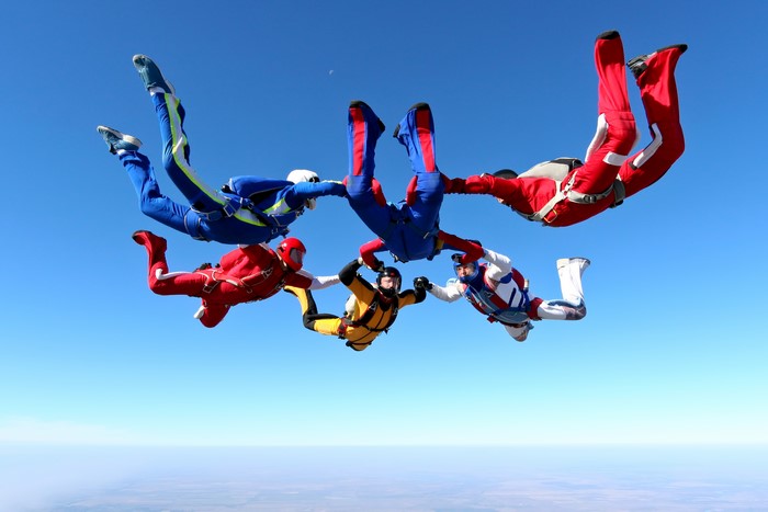 Group of skydivers in formation against a clear blue sky
