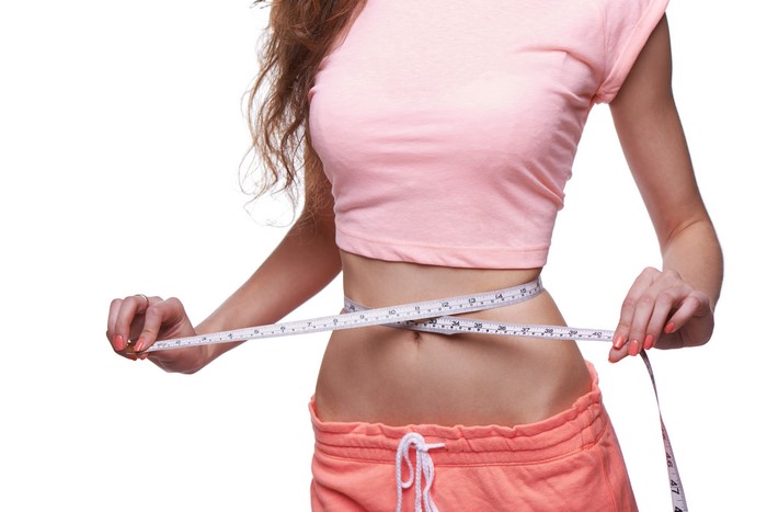 Woman measuring her waist with a tape measure