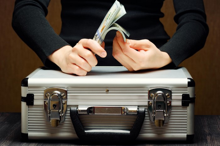 Hands counting money over a briefcase