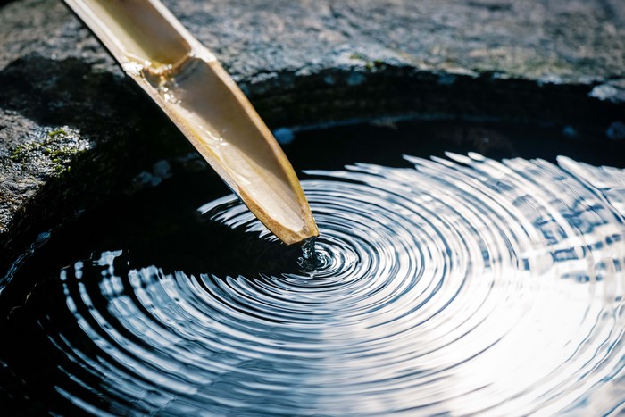 Bamboo spout dripping water creating ripples