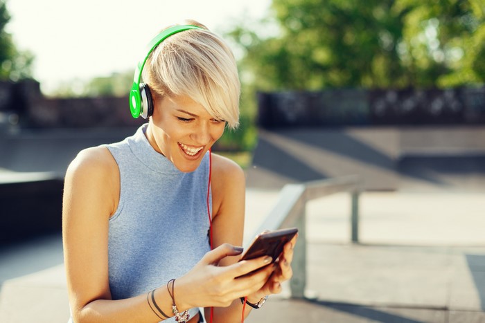 Blonde girl with headphones using smartphone