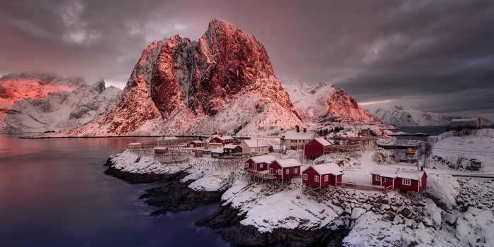 Red houses on snowy coast with mountains at sunset, Reine Nordland, Norway