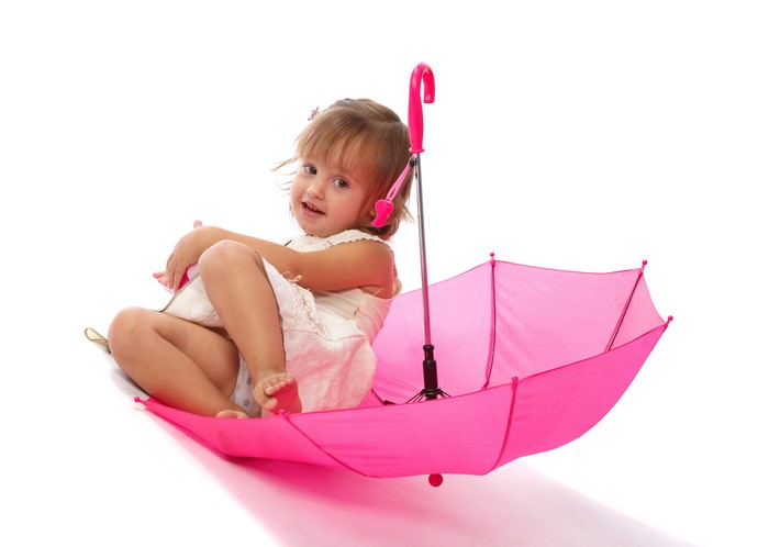 Little girl sitting in a pink umbrella