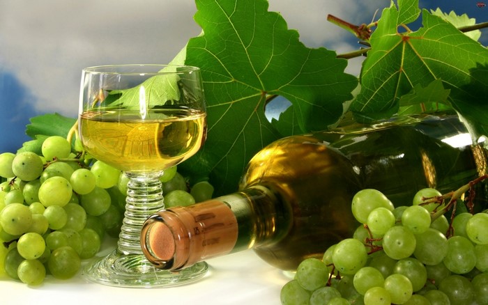 White wine in a glass and bottle with green grapes