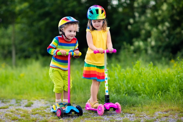 Two children with scooters and helmets