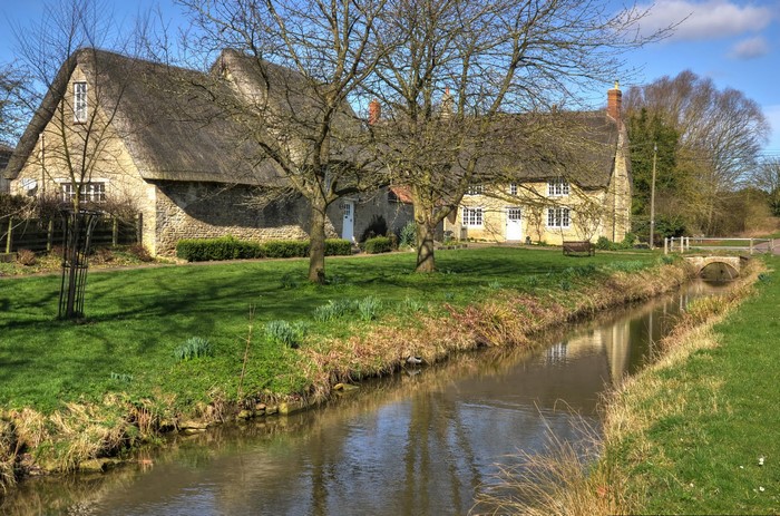 Thatched cottages by a stream in Northamptonshire, UK