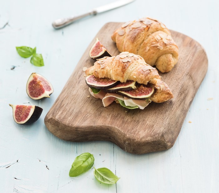 Croissant sandwich with figs and prosciutto on a cutting board