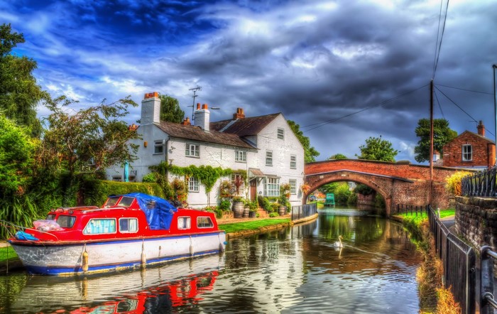 Motorboat on a canal in Lymm, England with a bridge