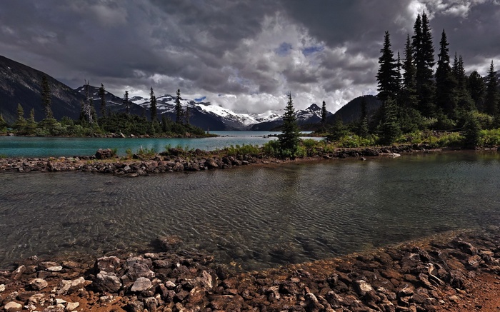 Mountain lake with snow-capped peaks and dark clouds
