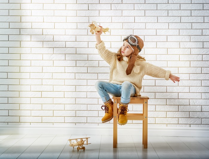 Little girl in pilot costume with toy airplane