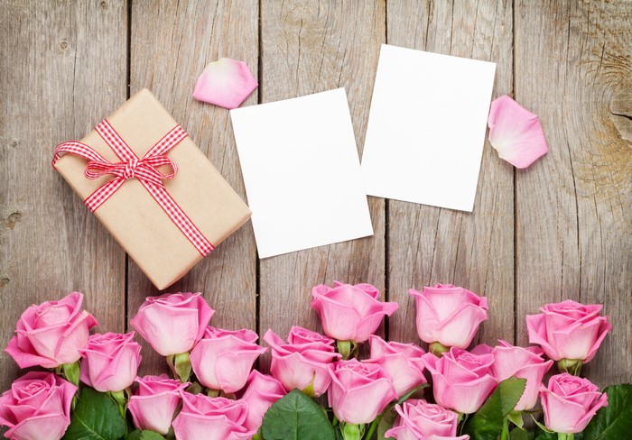 Gift box and pink roses on wood planks with blank cards