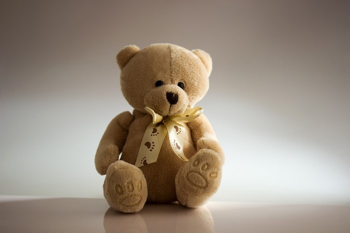 Teddy bear sitting with a yellow bowknot
