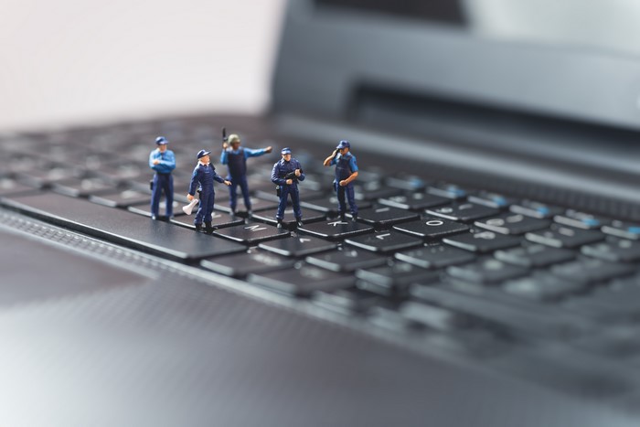 Miniature police figures on a laptop keyboard