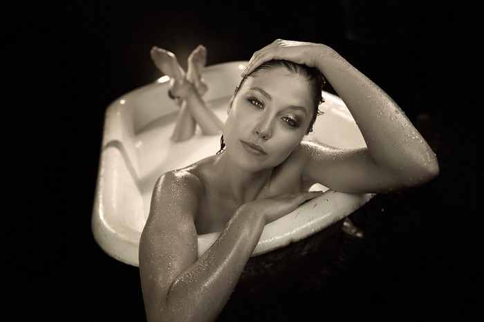 Woman in bathtub with hands on head